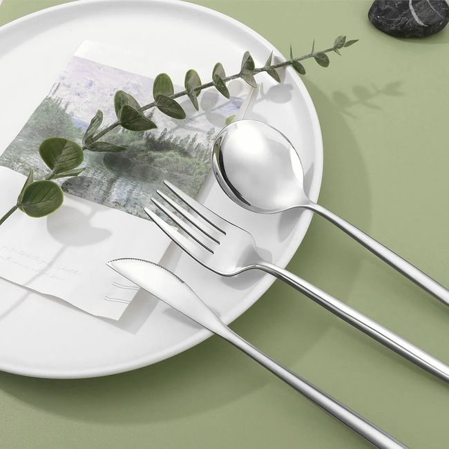 Detalle de cuchillo, tenedor y cuchara plateados sobre plato