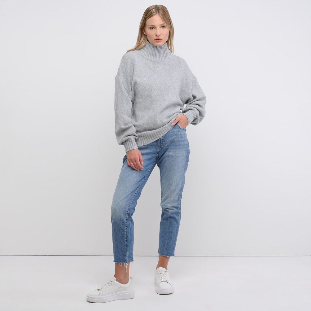 Woman in slouchy turtleneck sweater with relaxed jeans and sneakers